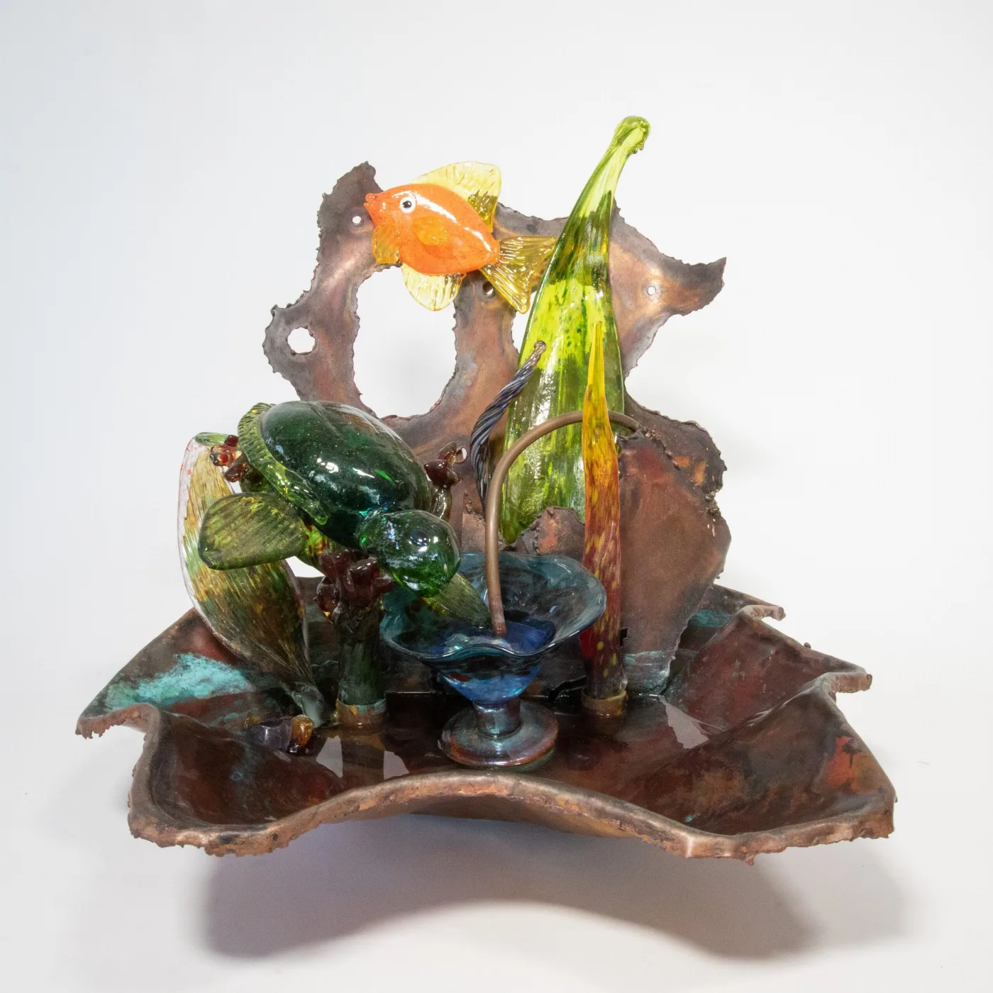 A sculptural reef of green and orange glass fish with blue glass and metal